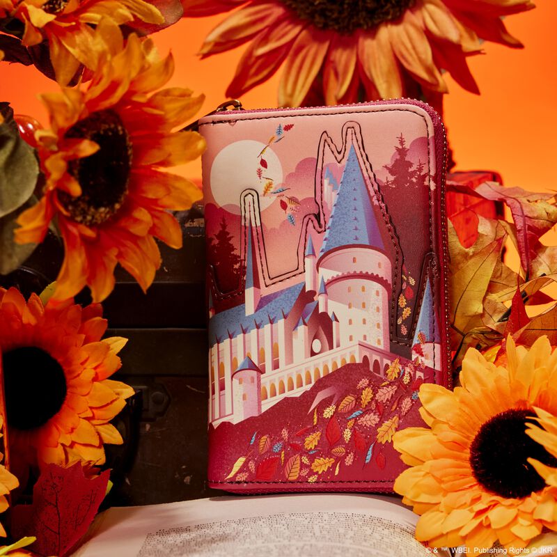 Image of our Hogwarts Fall Leaves Wallet sitting on a book and surrounded by flowers